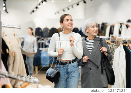 Two women customers watching large stock of clothes in clothing store Two women customers watching large stock of clothes in clothing store 122471254