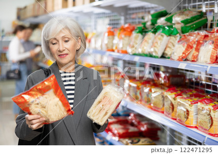 Senior woman in supermarket buys daily groceries, pasta Chinese noodles Senior woman in supermarket buys daily groceries, pasta Chinese noodles 122471295