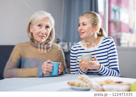 Mature mother and her adult daughter drink tea and chat 122471335