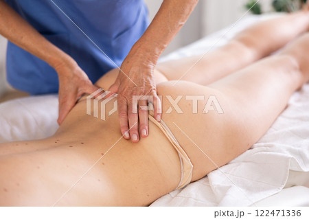 Masseuse doing back massage to young woman Masseuse doing back massage to young woman 122471336