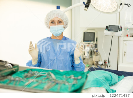 Elderly female veterinarian in surgical outfit standing in veterinary operating room Elderly female veterinarian in surgical outfit standing in veterinary operating room 122471457
