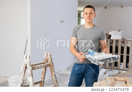Portrait of teenage boy with paint roller in building site Portrait of teenage boy with paint roller in building site 122471479