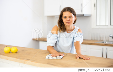 Positive woman cleaning kitchen table at home Positive woman cleaning kitchen table at home 122471568