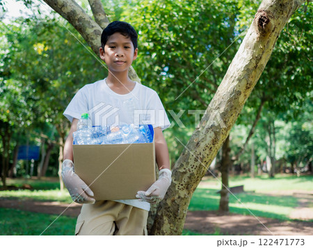 Reduction environmental pollution and recycle concept, Plastic-free, Junk food plastic packaging. Boy hold cardboard boxes for recycling and holding a recycle bin with plastic bottles in the outdoors. Reduction environmental pollution and recycle concept, Plastic-free, Junk food plastic packaging. Boy hold cardboard boxes for recycling and holding a recycle bin with plastic bottles in the outdoors. 122471773