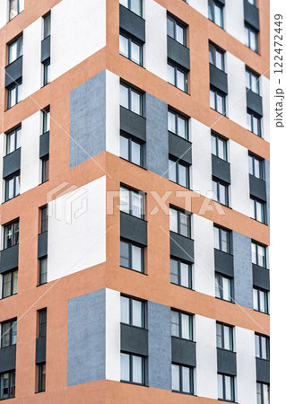 Modern apartment building facade, featuring orange, white and grey tones, with dark-framed windows with colorful accents. Urban housing concept Modern apartment building facade, featuring orange, white and grey tones, with dark-framed windows with colorful accents. Urban housing concept 122472449