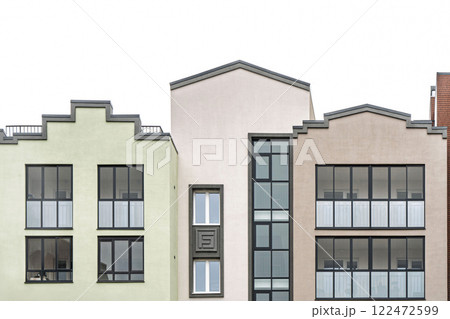 Contemporary residential building with geometric facade, glass windows, and balconies on bright sky background, urban architecture concept, front view 122472599