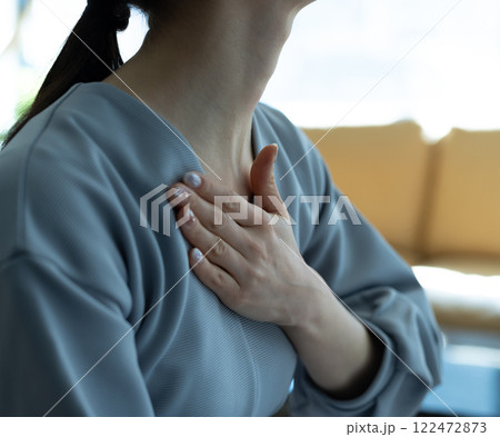 胸を押さえる女性の手元 122472873