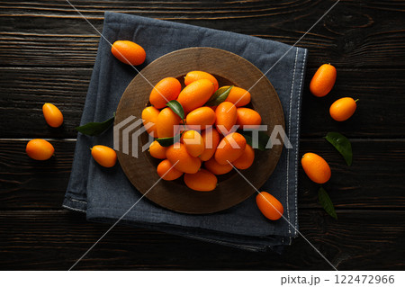 Kumquat on plate and towel on wooden background, top view Kumquat on plate and towel on wooden background, top view 122472966