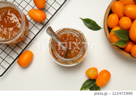 Kumquat in bowl and jars of jam on white background, top view 122472990