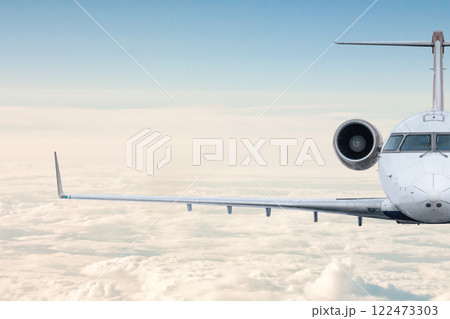 Front view of the luxury business jet flying in the air above the clouds 122473303