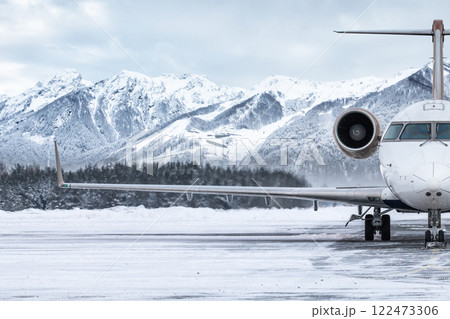 Front view of the luxury private jet on the winter airport apron on the background of high picturesque mountains 122473306