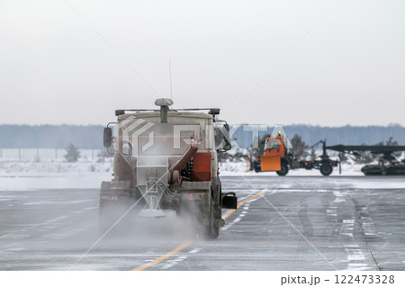 Snowblower cleans airport taxiway in a snowstorm Snowblower cleans airport taxiway in a snowstorm 122473328