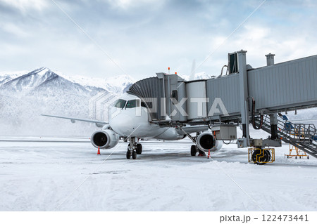 White passenger jet plane at the airgate at winter airport apron on the background of high picturesque mountains White passenger jet plane at the airgate at winter airport apron on the background of high picturesque mountains 122473441