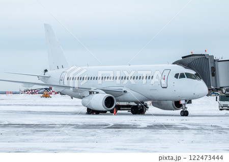 White passenger jet plane at the boarding bridge at winter airport apron White passenger jet plane at the boarding bridge at winter airport apron 122473444