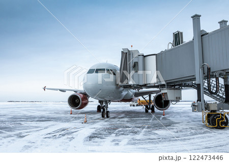 Passenger airplane at the airbridge at winter airport apron Passenger airplane at the airbridge at winter airport apron 122473446