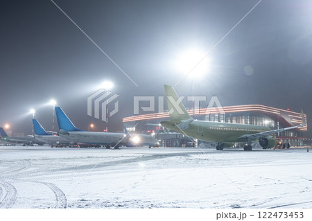 Passenger airplanes on the airport apron next to the terminal in a snowy winter night 122473453