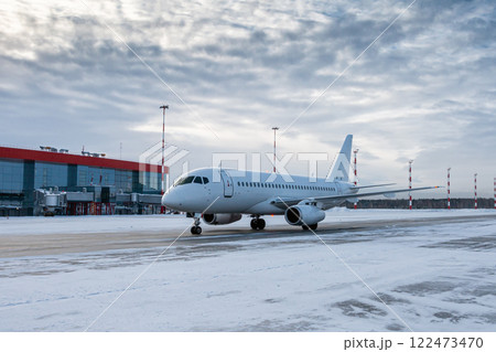 White passenger airplane taxiing on the airport apron at winter White passenger airplane taxiing on the airport apron at winter 122473470