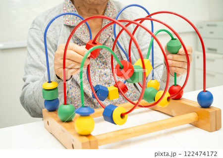 Asian elderly woman playing enhancing skill board game. 122474172