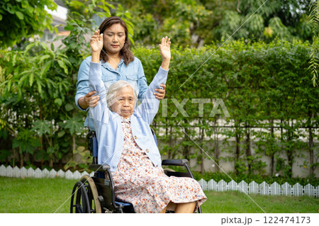 Caregiver help and care Asian senior woman patient sitting on wheelchair and exercise in park at hospital. 122474173