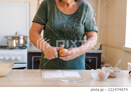 Woman is cutting a carrot on a table Woman is cutting a carrot on a table 122474874