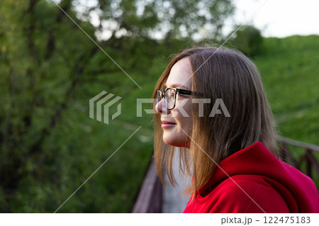 Contemplative moment by the wooden bridge surrounded by lush greenery in the golden hour light 122475183