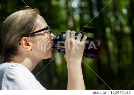 Refreshing sip in the heart of nature on a sunny day surrounded by lush green trees 122475188