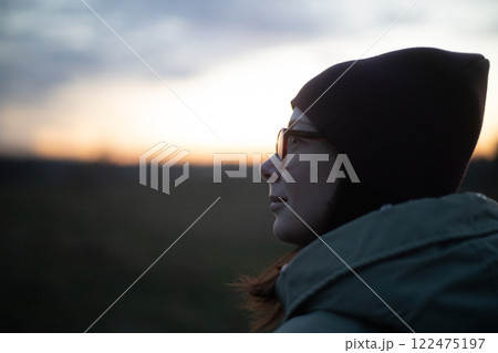 Contemplative moment at twilight with a serene woman gazing at the horizon Contemplative moment at twilight with a serene woman gazing at the horizon 122475197