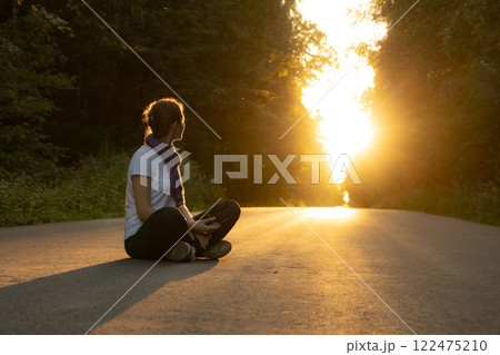 Meditative moment at sunset along a quiet forest road surrounded by nature 122475210