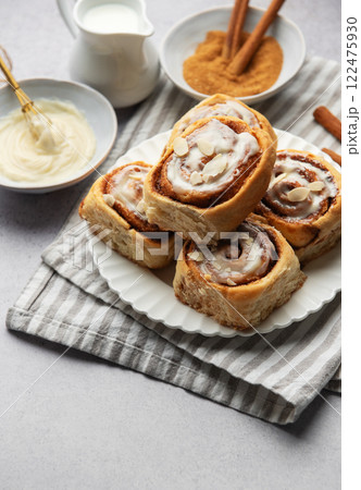 Freshly baked cinnamon rolls topped with icing and almond slivers 122475930