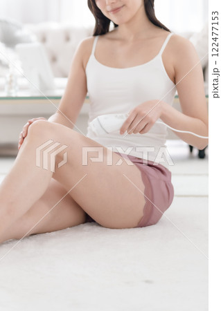 足に光脱毛気を当てる若い女性　顔無し　 122477153