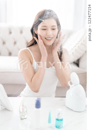 美顔スチーマーを頬に当てる美意識が高い若い女性 122477154