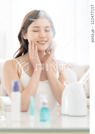 美顔スチーマーを頬に当てる美意識が高い若い女性 122477157