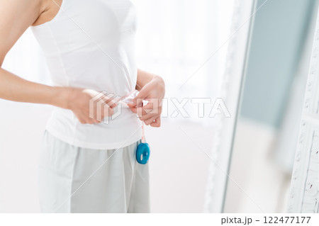 ウエスト周りを図る若い女性 ウエスト周りを図る若い女性 122477177