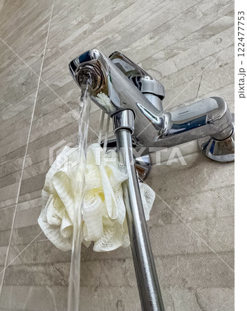 Running tap water on white bath sponge, bathroom closeup. High quality photo Running tap water on white bath sponge, bathroom closeup. High quality photo 122477753