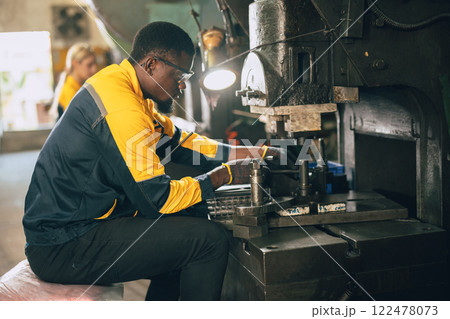 african black male worker working in heavy metal industry factory punching stamping steel machine 122478073
