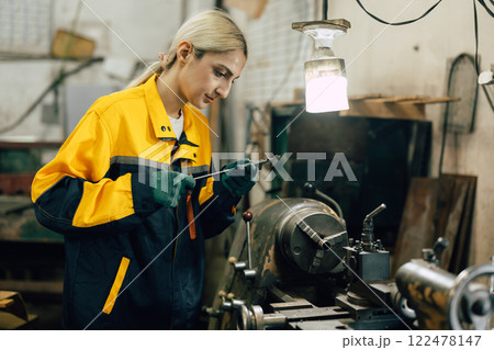 female worker using vernier caliper measuring metal part in lathe machine in heavy metal workshop female worker using vernier caliper measuring metal part in lathe machine in heavy metal workshop 122478147