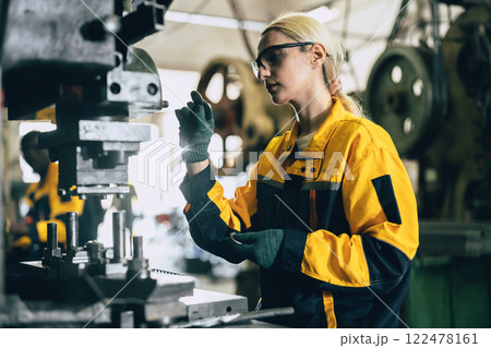Caucasian women worker working in heavy metal industry factory punching stamping steel machine Caucasian women worker working in heavy metal industry factory punching stamping steel machine 122478161