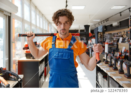 Man worker offering lumberjack axe high quality goods at hardware store 122478393