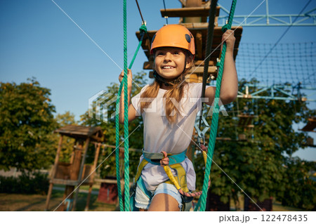 Cute little girl child walking rope ladder moving up on obstacle course Cute little girl child walking rope ladder moving up on obstacle course 122478435
