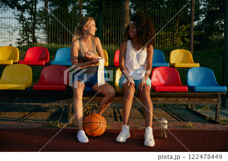 Female basketball players sitting at spectator seats having rest 122478449