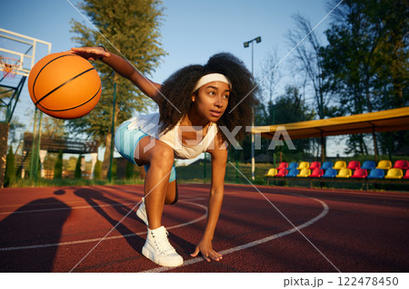 Young female basketball player in low start position dribbling ball Young female basketball player in low start position dribbling ball 122478450
