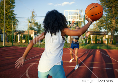 Teenage girls friends playing basketball enjoying excited game at outdoor court 122478451