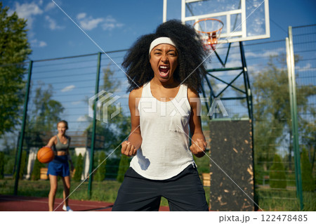 Excited young female basketball player screaming while looking at camera 122478485