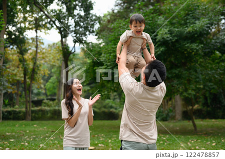 Happy father lifting his little son into the air enjoys spending leisure time together at outdoor 122478857