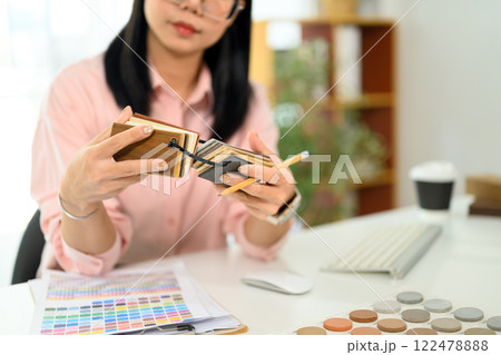Cropped shot decorator choosing laminate floor samples at desk. Home design and renovation 122478888