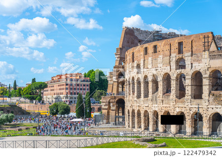 Crowds gather near the Colosseum in Rome, Italy, under a bright blue sky. This iconic landmark showcases ancient architecture and attracts tourists year-round with its historical significance. Crowds gather near the Colosseum in Rome, Italy, under a bright blue sky. This iconic landmark showcases ancient architecture and attracts tourists year-round with its historical significance. 122479342