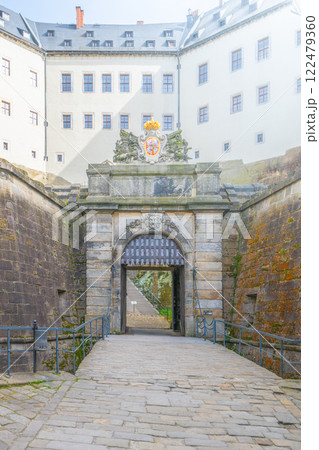 The majestic main entrance gate of Konigstein Fortress, located in Saxony, Germany, welcomes visitors with its impressive stone architecture and rich history. The majestic main entrance gate of Konigstein Fortress, located in Saxony, Germany, welcomes visitors with its impressive stone architecture and rich history. 122479360
