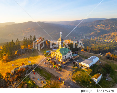The Tanvaldsky Spicak Lookout Tower stands majestically in the Jizera Mountains during a picturesque autumn evening, surrounded by vibrant foliage and panoramic mountain views. The Tanvaldsky Spicak Lookout Tower stands majestically in the Jizera Mountains during a picturesque autumn evening, surrounded by vibrant foliage and panoramic mountain views. 122479376
