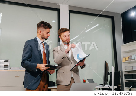 Diverse professionals collaborate on project analysis with financial graphs. Strategic teamwork and insights drive company growth and success. Diverse professionals collaborate on project analysis with financial graphs. Strategic teamwork and insights drive company growth and success. 122479755
