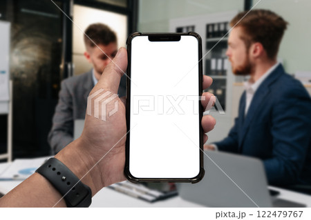 Business - technology and office concept - Hand holding mobile phone with blank screen in office. 122479767
